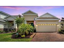 Charming single-Gathering home with brick driveway, two-car garage, manicured lawn, and lush tropical landscaping at 7423 Sungold Meadow Ct, Apollo Beach, FL 33572