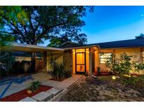 Charming home featuring stone accents, mature trees, and inviting front entrance under evening sky at 9812 N Pawnee Ave, Tampa, FL 33617