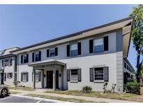 Exterior daytime view of a two-story building featuring black shutters, a gray color scheme, and a covered entryway at 1115 Rue Des Chateaux # 2B, South Pasadena, FL 33707