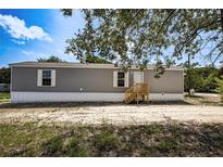 Well-maintained mobile home featuring light gray siding and a wooden porch with matching white trimmed windows at 16137 Melbourne St, Brooksville, FL 34604