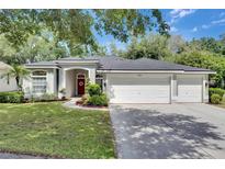 Charming single-story home with manicured lawn, red door, and three-car garage at 2010 Rutherford Dr, Dover, FL 33527