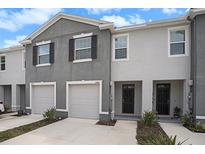 Charming gray two-story townhome featuring an attached garage and inviting front entrance at 32803 Pez Landing Ln, Wesley Chapel, FL 33543