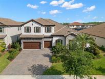Stunning two-story home with a tile roof, a paved driveway, a manicured lawn, and a three-car garage at 5043 Night Star Trl, Odessa, FL 33556
