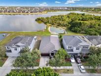 Aerial view of a suburban home with a lake view, surrounded by lush greenery and neighboring houses at 9031 Sienna Moss Ln, Riverview, FL 33578