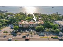 Aerial view of a low-rise building with lush landscaping and waterfront access at 950 Broadway # 103, Dunedin, FL 34698