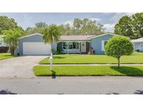 Charming blue single-story home with well-maintained landscaping, lush lawn, and a spacious two-car garage at 1101 Mclean St, Dunedin, FL 34698