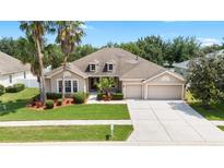 Charming single-story home featuring a well-manicured lawn, mature trees, and a two-car garage at 11845 Newberry Grove Loop, Riverview, FL 33579