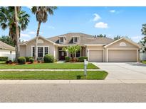 Charming single-story home with a three-car garage, well-manicured lawn, and mature palm trees at 11845 Newberry Grove Loop, Riverview, FL 33579
