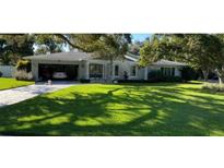Charming single-story home with a lush lawn, covered carport, and welcoming double door entry at 209 Rosery Rd, Belleair, FL 33756