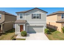 Charming two-story home featuring a gray facade, attached garage and well-maintained landscaping at 34855 Daisy Meadow Loop, Zephyrhills, FL 33541