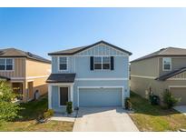 Charming two-story home with a blue exterior, well-maintained landscaping, and an attached garage at 34866 Daisy Meadow Loop, Zephyrhills, FL 33541