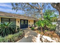 Inviting home exterior featuring a charming front entrance with double doors and lush landscaping at 6514 Sunhigh Dr, New Port Richey, FL 34655