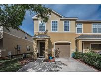 Charming two-story townhome with tan stucco exterior, attached garage, and well-maintained landscaping at 6902 47Th N Ln, Pinellas Park, FL 33781
