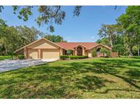 Charming single-story home with a three-car garage, well-maintained lawn, and mature trees at 7353 Dogwood Cres, Spring Hill, FL 34607