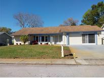 Charming single-story home featuring a well-manicured lawn, attached garage, and covered porch at 8313 Cavalry Dr, Hudson, FL 34667