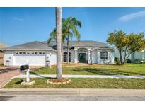 Charming single-story home with a well-manicured lawn and lush palm trees creating curb appeal at 8529 Regal Ln, Hudson, FL 34667