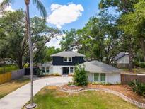 Charming two-story home with landscaped yard, long driveway, and mature trees creates a welcoming curb appeal at 1407 Jean St, Lutz, FL 33548