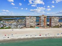 Expansive beach view with multiple condominium buildings, blue skies, and ocean waves in this aerial landscape at 17920 Gulf Blvd # 1302, Redington Shores, FL 33708