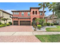 Mediterranean-style home featuring a brick driveway, two-car garage, and well-manicured landscaping with tropical plants at 2608 Calvano Dr, Land O Lakes, FL 34639