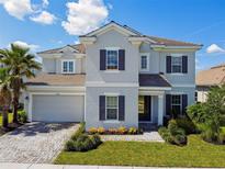 Beautiful two-story home featuring manicured lawn, neutral exterior, and paver driveway at 34084 Torrent Ln, Wesley Chapel, FL 33543