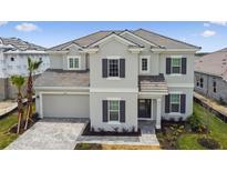 Elegant two-story home boasts a tile roof, gray exterior, and well-manicured front lawn at 34084 Torrent Ln, Wesley Chapel, FL 33543