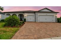 Charming single-story home featuring a brick driveway, two-car garage and beautifully landscaped front yard under a pink sky at 5670 Shorebird Br, Land O Lakes, FL 34638