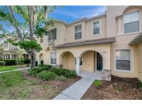 Charming two-story townhome featuring an inviting arched entryway, manicured landscaping, and a welcoming facade at 6842 Dartmouth Hill St, Riverview, FL 33578