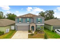 Charming two-story home with grey siding, teal shutters, manicured landscaping, and a two-car garage at 13380 Great Plains Dr, Riverview, FL 33579
