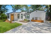 Charming home with a bright yellow front door, clean white exterior, and a modern driveway at 1715 N Alexander Rd, Tampa, FL 33603