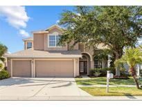 Charming two-story home with a three-car garage, well-maintained lawn, and mature landscaping at 1858 Mira Lago Cir, Ruskin, FL 33570