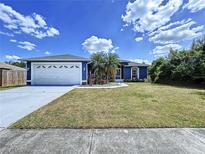 Charming blue home featuring an attached two-car garage, well-manicured lawn, and mature palm trees at 21626 Rosewood Ct, Lutz, FL 33549
