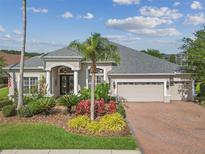Charming home featuring lush landscaping, a brick driveway and an attached two car garage at 26701 Winged Elm Dr, Wesley Chapel, FL 33544