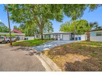 Charming home featuring lush landscaping, mature trees, and a freshly painted driveway leading to an attached garage at 8444 8Th N Way, St Petersburg, FL 33702