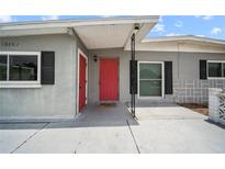 Home exterior with red front door, black shutters, and neutral gray paint at 10602 Camelia Dr, Port Richey, FL 34668