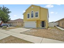 Bright yellow two-story home with a two car garage, black door, and well-maintained lawn at 11323 Ivy Flower Loop, Riverview, FL 33578