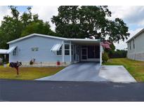 Charming single-story home with covered parking, manicured lawn, and patriotic American flag at 37643 Campo Ave, Zephyrhills, FL 33541