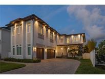 Elegant two-story home featuring manicured landscaping, brick driveway, and warm exterior lighting at 429 Erie Ave, Tampa, FL 33606