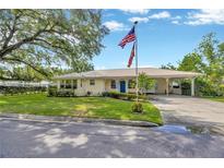 Charming single-story home featuring a metal roof, well-manicured lawn with a flagpole, and a convenient carport at 509 N Walker St, Plant City, FL 33563