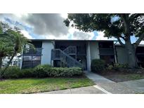 Condo's exterior showcasing the front entrance, mature trees, a partial lawn, and lush landscaping at 11201 122Nd Ave # 103, Largo, FL 33778