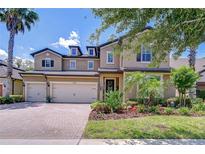 Stunning two-story home featuring a three-car garage, beautiful landscaping and a brick paved driveway at 11205 Lark Landing Ct, Riverview, FL 33569