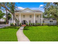 Charming two-story white brick home featuring a columned front porch and landscaped yard at 1207 S Druid Ln, Tampa, FL 33629