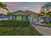 Charming home with a manicured lawn, lush hedge, and a welcoming, freshly painted exterior with teal shutters and door at 1727 New Hampshire Ne Ave, St Petersburg, FL 33703