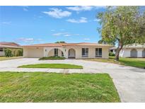 Charming home with a red tile roof, lush green lawn, and an inviting arched entryway at 2146 Egret Drive, Clearwater, FL 33764