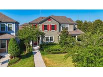 Charming two-story home featuring a landscaped yard, red shutters, and a welcoming front porch entrance at 5807 Circa Fishhawk Blvd, Lithia, FL 33547