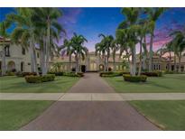 Elegant home with a brick driveway, lush landscaping, and stately palm trees at twilight at 624 Balibay Rd, Apollo Beach, FL 33572