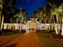 Beautifully lit Mediterranean style home at night with a long brick driveway and tropical landscaping at 624 Balibay Rd, Apollo Beach, FL 33572
