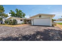 Charming single story home boasts a white garage door and a cracked dark driveway at 6638 12Th N Ter, St Petersburg, FL 33710