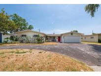 Charming single-story home featuring a red front door and attached garage with a spacious front yard at 6638 12Th N Ter, St Petersburg, FL 33710