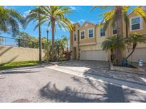 Charming tan townhome with a two-car garage, beautiful palm trees, and a brick-paved driveway at 789 Grand Cypress Ln, Tarpon Springs, FL 34689