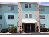 Three-story condo complex with light blue accents, neutral colors, and landscaping around the entrance at 11447 Park Blvd # 301, Seminole, FL 33772